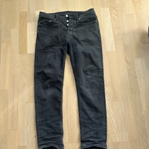 Svarta jeans från Acne Studios 30/32 - Snygga svarta jeans från Acne Studios i klassisk femficksmodell. Jeansen har raka ben, knappgylf och diskret Acne Studios-lapp bak i midjan. Materialet är mjukt denim i bomull med en mörk tvätt som ger en stilren look.
