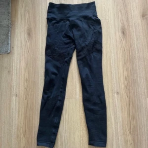 Svarta träningstights från Aim’n  - Svarta seamless leggings med hög midja och snygga meshdetaljer längs benen. Stretchigt material som sitter tight och bekvämt, perfekt för träning eller chill. Bred linning för extra stöd och stilren look.