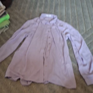 Ljuslila skjorta från Wera Stockholm - Säljer en stilren ljuslila skjorta från Wera Stockholm i storlek 42. Skjortan har klassisk krage, långa ärmar och knappar framtill. Materialet känns mjukt och lätt, perfekt för dig som gillar en clean och enkel look med lite färg.