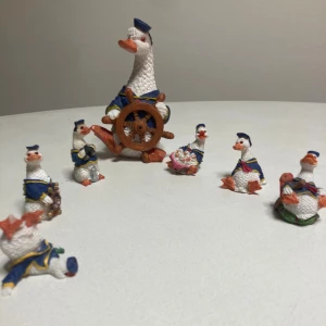 Årets julklapp ~ hur söta som helst  - Bilderna visar en samling dekorativa porslinsfigurer föreställande sjömansklädda gäss. Setet består av sju figurer i olika storlekar och poser, alla med fina detaljer och färger. Perfekt för samlare eller som charmig inredningsdetalj. Inga synliga skador eller slitage.