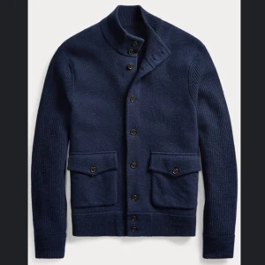Ralph Lauren cardigan  - Säljer en mörkblå kofta från Polo Ralph Lauren i ull. Koftan har ribbade ärmar, hög krage med knappar och två stora fickor framtill med lock. Perfekt för lager-på-lager och snygg till jeans eller chinos.