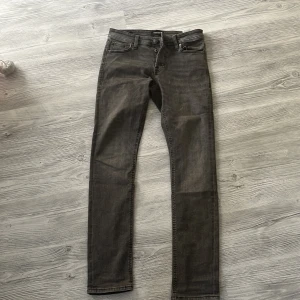 Grå slim jeans Jack & Jones Glenn - Slim Glenn jeans från Jack & Jones i en snygg grå tvätt. Modellen har smal passform, klassisk femficksdesign och normal midja. Jeansen är tillverkade i stretchig denim för extra komfort och har subtila slitningar för en cool look.