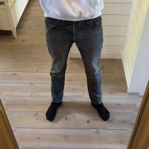 Svarta Jack & Jones tapered jeans - cool look☑️ - Svarta Jack & Jones tapered jeans i strl 28/30. Sitter bra och har ett slitet benslut - ger en ren och snygg look. Har ett litet hål, en liten fläck och en spricka på patchen (skriv för bild) men påverkar inte helhetsbilden. 🍂Perfekta för hösten ☑️Snygg passform ✅Endast 259kr!🎁Fri frakt resten av veckan! 