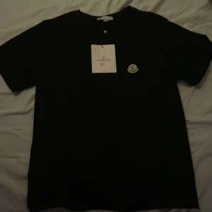 Svart Moncler t-shirt med logga - Säljer en svart moncler t shirt i stl L men passar M då de är små i storleken. Säljer då jag behöver pengar 