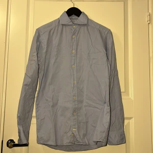 Ljusblå skjorta ETON - Säljer en stilren ljusblå skjorta från ETON. Mycket snygg och hög kvalitativ skjorta. Lite skrynklig på bilderna tyvärr. Den är i storlek 37 slim vilket motsvarar en storlek S. Hör av er vid minsta fundering eller om ni vill ha fler bilder. Kolla gärna in min profil för fler stilrena kläder⭐️