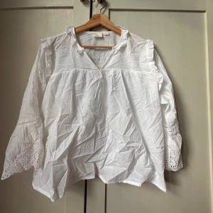 Vit blus med spets från Gina Tricot - Superfin vit blus från Gina Tricot med v-ringning och långa ärmar. Ärmarna har broderade spetsdetaljer och volangkant. Blusen är i luftig bomull och har en avslappnad passform med romantiska vibbar. (snyggare styrkt) Helt ny dock har jag tagit av prislappen. Ny pris 399 kr men säljer för 200