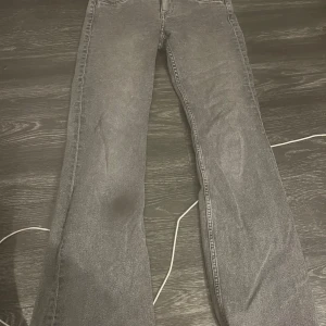 Grå bootcut jeans med låg midja  - Snygga grå jeans med bootcut passform och klassiska femficksdetaljer. Jeansen har en rak midja och är tillverkade i ett mjukt denimtyg som ger en avslappnad vibe. Perfekta för dig som gillar en tidlös look med lite extra edge.