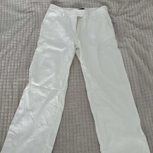 Vita linnebyxor från BikBok - Snygga vita linnebyxor från BikBok i rak modell. Byxorna har hällor för bälte, sidfickor och stängs med hake och dragkedja. Perfekta för en fräsch och stilren look under varmare dagar.