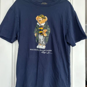 Mörkblå Polo Bear t-shirt Ralph Lauren - Snygg mörkblå t-shirt från Ralph Lauren med ikoniskt Polo Bear-tryck på bröstet. 