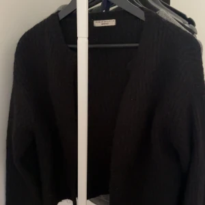 Svart stickad kofta från Gina Tricot - Mysig svart stickad kofta från Gina Tricot med öppen front och lång ärm. Perfekt för lager-på-lager och enkel att matcha med olika outfits. Klassisk och tidlös design som funkar året runt.