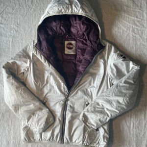 Vit colmar jacka - Snygg vit pufferjacka från Colmar med foder och huva. Jackan har dragkedja framtill, två fickor med dragkedja och elastiska muddar. Klassisk Colmar-logga på ärmen och insidan. Perfekt för kyliga dagar och riktigt skön passform.