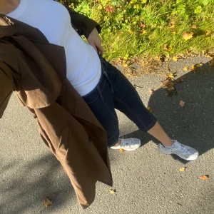 Cropped flare jeans - Säljer ett par mörkblå croppade jeansbyxor med snygga kontrastsömmar och uppvikta benslut. Byxorna har hög midja och stängs med dubbla knappar och dragkedja. Perfekta för dig som vill ha en cool och avslappnad stil.
