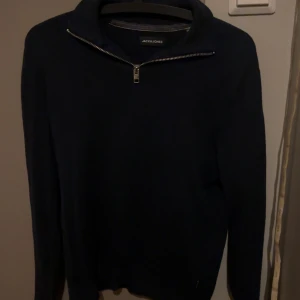 Mörkblå half zip-tröja Jack & Jones - Mörkblå långärmad tröja från Jack & Jones med snygg half zip-dragkedja vid kragen. Enkel och stilren design som passar perfekt till jeans eller chinos. Mjuk och skön, perfekt för kyligare dagar.