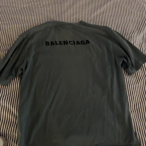 Blå t-shirt från Balenciaga - Säljer en grön t-shirt från Balenciaga i storlek S. T-shirten har klassisk passform, rund halsringning och svart Balenciaga-tryck både fram och bak. Loggan är broderad. Tillverkad i mjuk bomull för en skön känsla. Perfekt för dig som gillar stilrena designer och streetwear. T-shirten är givetvis äkta och köpt i Frankrike för 8000kr. Ganska oversized så sitter mer som en oversized M (se bild) är 188cm 86kg