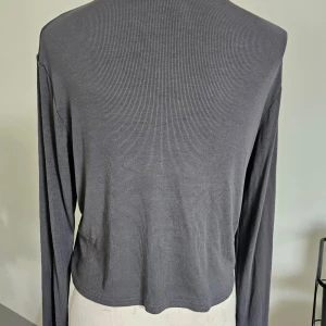 Mörkgrå ribbad långärmad topp XL - Säljer en mörkgrå ribbad långärmad topp från h&m divided i storlek XL. Toppen har en croppad passform, rund halsringning och är tillverkad i mjukt, stretchigt material. Perfekt för lager-på-lager eller som den är till jeans eller kjol.