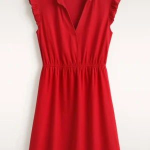 Röd kort klänning från H&M - Supersöt röd klänning från H&M med volangdetaljer vid ärmhålen och markerad midja. Klänningen är ärmlös, har v-ringning och är i en mjuk, lätt bomullskvalitet. Perfekt för dig som vill ha en enkel men snygg look.