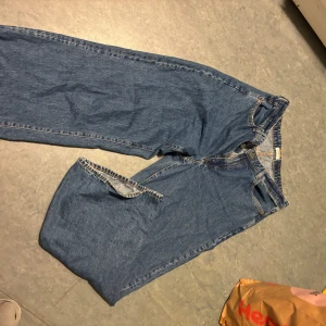 Blå jeans från Lindex, storlek 46 - Klassiska blå jeans från Lindex i rak modell med normal passform. Jeansen har fem fickor, gylf med dragkedja och knapp samt snygga kontrastsömmar. Perfekta för dig som gillar en enkel och tidlös look.