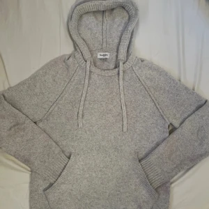 Grå stickad hoodie från Goodfellow - Mysig grå stickad hoodie från Goodfellow & Co i storlek M. Tröjan har huva med snörning, känguruficka och ribbade muddar. Perfekt för kyliga dagar och enkel att matcha med jeans eller mjukisbyxor.        Tja, säljer denna fina stickade hoodie från Goodfellow. Inga defekter bortsett från att den har milda ”fläckar” av rosa/röd färg på vissa (ett som är synligt) ställen. Annars riktigt schysst och syns inte på avstånd (dvs. någon meter)