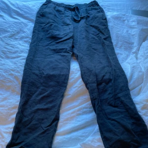 Svarta linnebyxor från A Day's March - Svarta linnebyxor från A Day's March med avslappnad passform och elastisk midja med snörning. Perfekta för en chill och stilren look. Byxorna är raka i modellen och har fickor i sidorna.