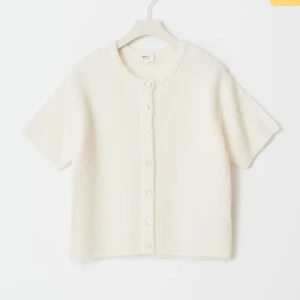 Vit kofta från Gina Tricot i ullmix - Supermjuk och ribbstickad vit kofta från Gina Tricot i ullblandning. Koftan har rund hals, korta ärmar och knäpps med vita knappar framtill. Perfekt för lager-på-lager och en clean look. Nypris 360kr