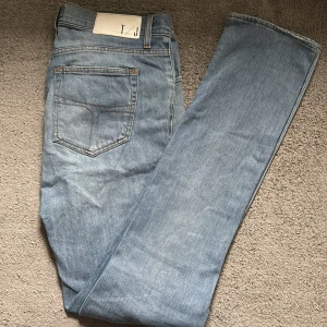 Ljusblå jeans Mustang Sharp 33/34 - Säljer ett par ljusblå jeans från Mustang i modellen Sharp. Klassisk femficksdesign med kontrastsömmar och vit patch med T/J på linningen. Jeansen har rak passform och är tillverkade i slitstarkt denimtyg.