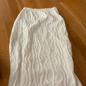 Vit långkjol från SHEIN i XS - Supersnygg vit långkjol från SHEIN i storlek XS. Kjolen har ett vågigt, strukturerat mönster i tyget och är fodrad för extra komfort. Resår i midjan gör den enkel att ta på och av. Perfekt för dig som gillar stilrena och trendiga plagg.