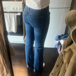  blå jeans bootcut - Säljer ett par klassiska jeans i mörkblå tvätt. De har låg/mid midja under naveln. Utsvöngda ben med lätt bootcut och femficksdesign. Jeansen är i ett mjukt och slitstarkt bomullsmaterial, perfekta för dig som gillar en tidlös och avslappnad look. Använda FÅTAL gånger pga de är snäppet för korta för mig💕passar även s/36