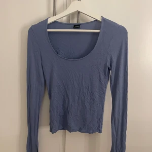 Ljusblå långärmad topp Gina Tricot - Säljer en ljusblå långärmad topp från Gina Tricot i storlek S. Toppen har en rundad, djup halsringning och är figurnära i passformen. Materialet är mjukt och stretchigt, perfekt för en chill och stilren look.