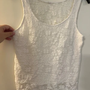 Vit spetslinne med blommönster strl: S - Säljer ett vitt ärmlöst linne med vackert blommigt spetsmönster. Toppen har rund halsringning och är figurnära i modellen. Perfekt för dig som gillar romantiska och feminina detaljer. Materialet är mjukt och stretchigt för extra komfort.