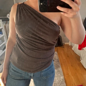 Zara brun fest topp  - Säljer en brun one shoulder topp med snygg drapering och smal axelrem på ena sidan. Jättefint material, och perfekt brun färg! Använd en gång .