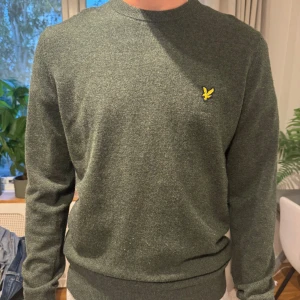 Grön stickad tröja från Lyle & Scott - Mörkgrön stickad tröja från Lyle & Scott med klassisk rund hals. Perfekt för dig som gillar stilren och enkel design. Kan gå ner i pris vid snabb affär!