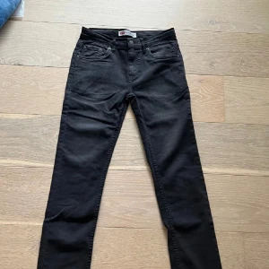 Svarta Levi's 512 slim jeans W28 L32 - Svarta Levi's 512 slim jeans med klassisk femficksdesign och smal passform. Jeansen har normal midja och är tillverkade i stretchigt denimtyg för extra komfort. Snygga detaljer som nitar och Levi's logga på bakfickan.                     W28 L32