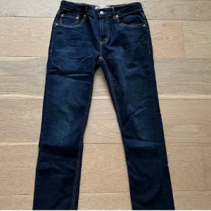Levi's 512 mörkblå jeans slim fit W28 L32 - Mörkblå Levi's 512 jeans med slim fit och klassisk femficksdesign. Jeansen har kontrastsömmar, bälteshällor och Levi's ikoniska läderpatch bak. Tillverkade i jeansmaterial med snygg rak passform och subtilt smalare ben.                      W28 L32