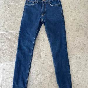 Blå skinny jeans från Nudie Jeans - Modell Mellow Mae i färgen Indigo Rain, stl 26/30. Passar både tjej och kille. Tvättade ett fåtal gånger och sparsamt använda. Innerfickorna är förlängda, hos sömmerska, för att en mobiltelefon ska få plats.