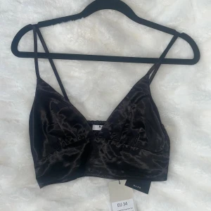 Svart satin linnetopp från NA-KD - Oanvänt supersnyggt svart linnetopp i glansigt satinmaterial från NA-KD. Toppen har smala justerbara axelband, v-ringad front och smockad rygg för extra komfort⚡️