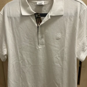 Vit Burberry t-shirt med krage - Nu säljer jag min vita Burberry piké i storlek M. Den är i nyskick och endast använd 2 gånger – jättefräsch! Säljer den eftersom den är lite för stor på mig. 