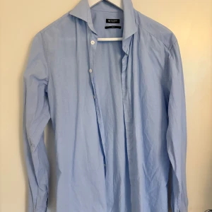 Ljusblå skjorta Tiger of Sweden - Snygg ljusblå skjorta från Tiger of Sweden i slim fit-modell. Skjortan har klassisk krage, långa ärmar och knäppning framtill. Tillverkad i bomull för en skön känsla och stilren look.