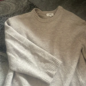 Beige stickad tröja från Gina Tricot - Mysig beige stickad tröja från Gina Tricot i ullblandning. Tröjan har rund halsringning, ribbade muddar och lång ärm. Perfekt för lager-på-lager och chill dagar.