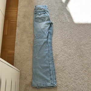 Ljusblå bootcut jeans Gina Tricot - Ljusblå jeans från Gina Tricot i klassisk bootcut-modell. Jeansen har fem fickor, snygga detaljer med knappar på bakfickorna.