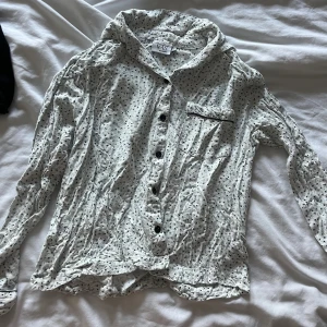 Vit blommig pyjamas skjorta från VRS Woman - Vit skjorta från VRS Woman med små blommiga mönster i svart och grönt. Behöver strykas men annars bra
