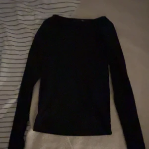 Svart långärmad tröja från 157 - En enkel svart långärmad tröja från 157 med rund hals. Perfekt för lager-på-lager och passar till jeans eller kjol. Mjuk och skön känsla, med normal passform och stilren look.