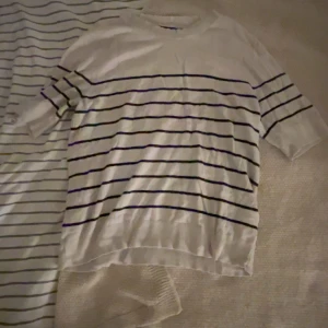 Vit randig t-shirt med svarta linjer - Vit t-shirt med svarta horisontella ränder. Klassisk rund halsringning och korta ärmar. Perfekt för en avslappnad och stilren look. Tunt och mjukt material som känns skönt mot huden.