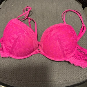 Rosa spets puch up bh  från Censored 80B - Säljer en snygg rosa puch up bh från Censored i storlek 80B. Bh:n har vadderade kupor och är dekorerad med blommig spets och tunna axelband. Perfekt för dig som gillar färgstarka underkläder med fina spetsdetaljer.