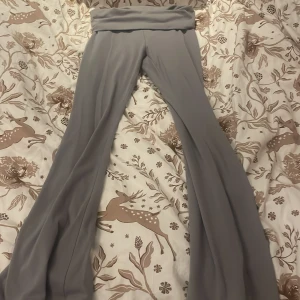 Grå bootcut yogapants från H&M - Snygga grå bootcut yogapants från H&M med bred, mjuk midja som kan vikas ner. Byxorna har en skön passform och är tillverkade i ett stretchigt material som känns bekvämt hela dagen. Perfekta för dig som gillar en avslappnad men trendig stil.