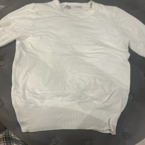Vit tröja från Zara i bomull - Enkel och stilren vit tröja från Zara i storlek S. Tröjan har rund halsringning, långa ärmar och bred ribbad mudd nedtill. Perfekt för lager-på-lager och passar till många olika outfits.