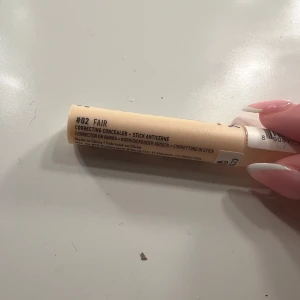NYX Pro Fix Stick Concealer Fair - Endast testad, NYX Pro Fix Stick Concealer i nyansen #02 Fair. En krämig concealer i stiftformat som är perfekt för att täcka ojämnheter och mörka ringar. Ljusbeige färg, enkel att applicera och smidig att ha med i väskan.