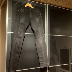 Svarta Replay Grover jeans - Snygga svarta jeans från Replay, modell Grover. Klassisk femficksdesign med dragkedja och knapp, raka ben och diskreta detaljer. Jeansen är tillverkade i ett mjukt och stretchigt bomullsmaterial som sitter skönt hela dagen.