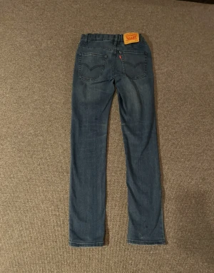 Levi's 511 blå jeans straight fit - Säljer ett par klassiska Levi's 511 jeans i blå tvätt med straight fit. Jeansen har fem fickor, knapp och dragkedja fram samt den ikoniska Levi's-lappen bak. Perfekt passform och snygg faded effekt på låren. Passar dig som gillar tidlös stil.