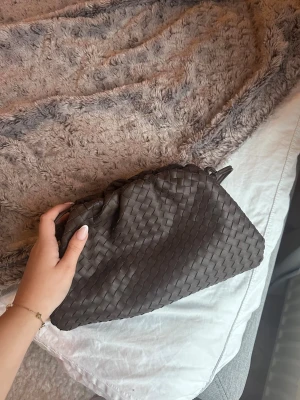 Brun flätad axelväska i skinn - Brun Jackie väska. Går att ha både som clutch om man stoppar in banden men även med band (som går att justera i längd). Super fint skick!! 💕Köpt för 2400kr.