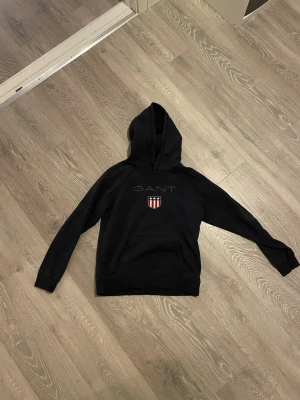 Gant hoodie  - Mörkblå gant hoodie med den klassiska gant logan i mitten av tröjan. Tröjan är i storlek S och är i ett bra skick. 